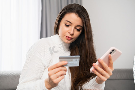 一位年轻美女拿着信用卡在网上购物的照片