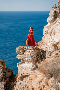 在大海的映衬下，一位身着红色飞裙的女子在风中飘扬。