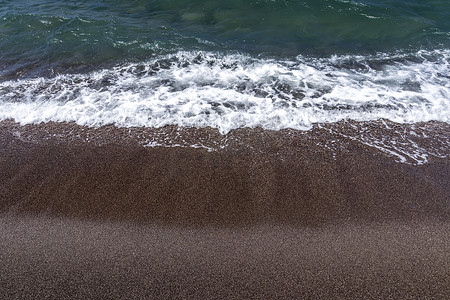 沙滩冲浪摄影照片_在沙滩上用黑色的火山岩沙滩冲浪。