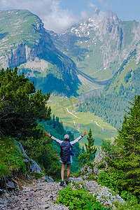 夏季度假时，亚洲女性背着背包和登山靴在瑞士阿尔卑斯山徒步旅行