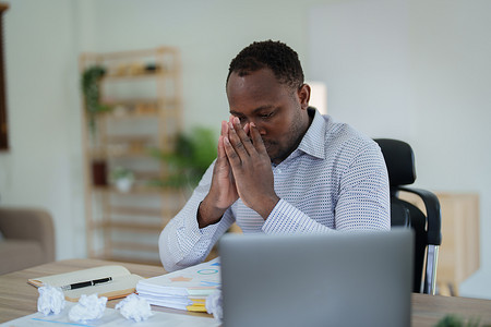 精疲力尽的美国非洲商人在压力下处理许多文书工作文件、偏头痛发作、自由职业者、在家工作
