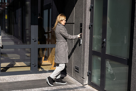 门智能锁摄影照片_女人使用智能手机将 smartlock 锁在入口门上。