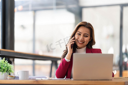 微笑美丽的亚洲女商人分析显示市场变化的图表和图表，并在办公室手持智能手机。
