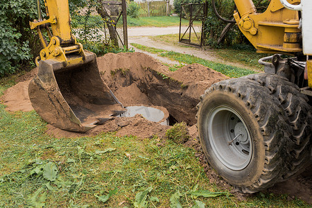 一桶带有一堆沙土的挖掘机在工业区埋下水道混凝土环