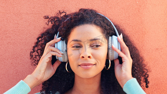 听收音机摄影照片_音乐、耳机和一个快乐的黑人妇女的脸，在墙壁背景下听收音机、歌曲和声音。