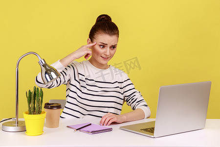 不悦摄影照片_女工用手指在笔记本电脑屏幕上做出愚蠢的手势，表情不悦疲倦。