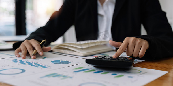 使用计算器分析财务账户的商业会计女性的近手检查公司的费用和预算