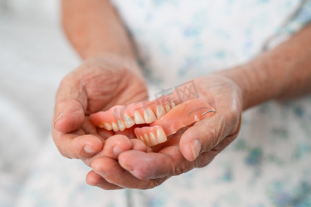 亚洲老年妇女患者坚持使用假牙，健康强大的医疗理念。
