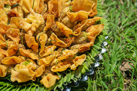 一盘饺子摄影照片_背景草地上一盘香蕉叶和铝上的金袋图片