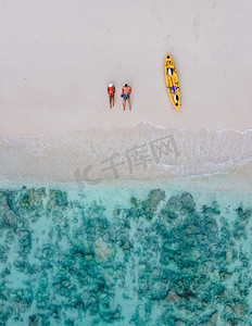 在皮划艇度假期间，无人机可以看到躺在泰国皮皮岛海滩上的一对夫妇