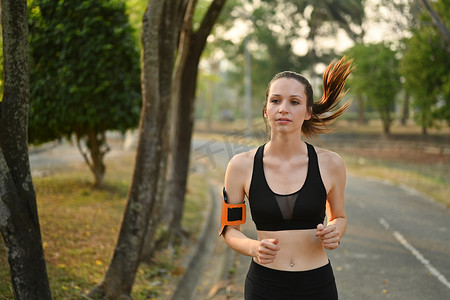 穿着运动服在公共公园慢跑的女运动员很高兴。