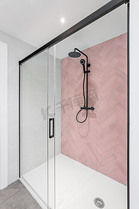 有桃红色和白色瓦片、雨喷头、手扶的阵雨和玻璃门的现代卫生间。