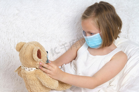 生病的少女为玩具戴上医用防护面具。