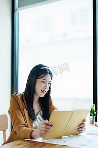 财务、规划、营销和会计，亚洲员工在工作中使用笔记本检查财务报表的肖像