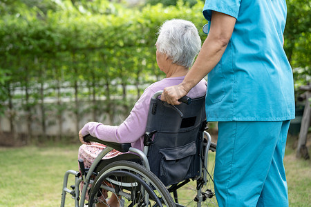 老女性摄影照片_护理医院公园轮椅上的医生护理人员帮助和护理亚洲老年或老年老妇人患者，健康强健的医疗理念