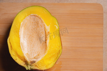 芒果，鲜熟芒果的特写，切成两半，放在切木板上