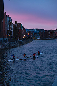 波兰格但斯克 2022 年 3 月，一群 sup 冲浪者站起来桨板，在老城黄昏的莫特拉瓦河和运河城一起划桨。