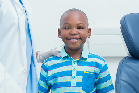 微笑的男孩站在被裁掉的牙医旁边