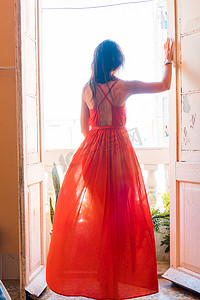 哈瓦那公寓旧阳台上穿着红色裙子的年轻漂亮女人