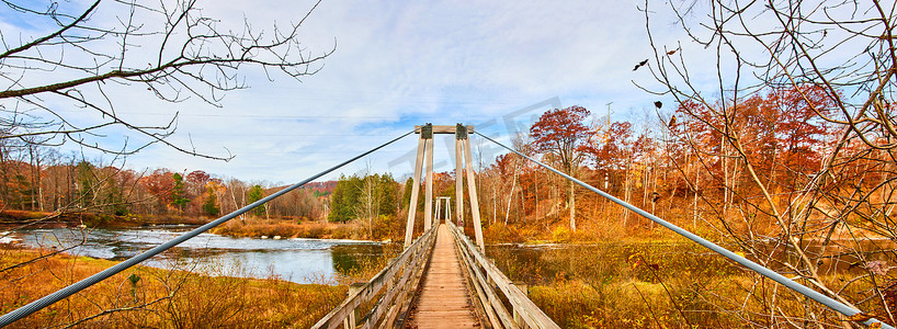 森林吊桥摄影照片_横跨密歇根河的长吊桥全景，秋叶色