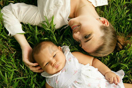 母亲爱抚躺在草地上的小女儿