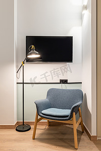 现代舒适扶手椅的特写，配有深蓝色内饰明亮的天花板灯和金属落地灯，房间内有白色墙壁和木镶木地板。