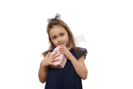 一个小女孩的画像，她带着一个粉红色的心形盒子，带着惊喜，被白色背景隔离了。