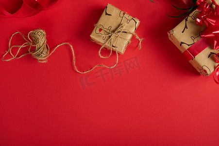 圣诞礼物包裹在带有鹿图案的包装纸中，并在红色背景的顶部用麻绳绑起来