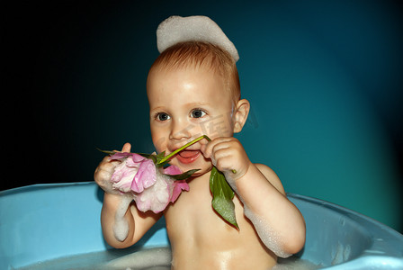 小男孩手里拿着花在洗澡。