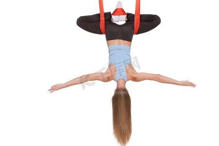 空中飞人摄影照片_年轻女子在无缝白色背景的吊床上做反重力空中瑜伽。