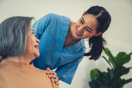 一位护理人员将她的手放在一位心满意足的老年患者的肩膀上。