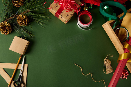 绿色背景中带有包装材料、装饰带、松果和常绿杉树枝的圣诞模型