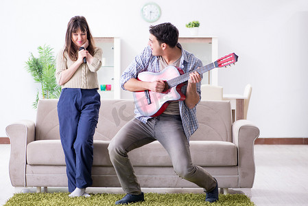 年轻家庭在家唱歌和演奏音乐