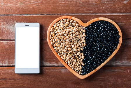 心板和智能手机空白上的黑豆和大豆种子