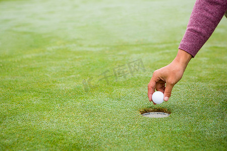 云洞摄影照片_高尔夫球手试图将球弹入洞中