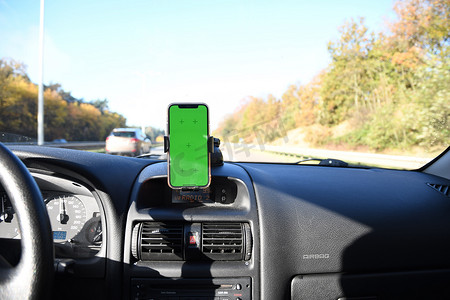 定位导航导航摄影照片_用于导航的汽车挡风玻璃支架中带绿色屏幕的智能手机