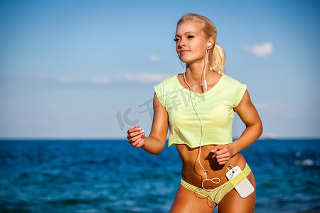 大海背景下戴着耳机跑步的女人