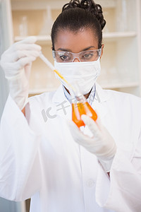 集中的科学家用吸管检查橙色液体