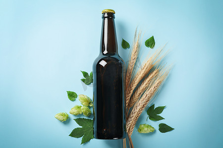 蓝色背景中的一瓶啤酒、小麦和蛇麻草
