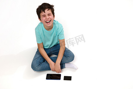 一个不满的白人男孩的头像，用智能手机和信用卡坐在白色背景上表达悲伤