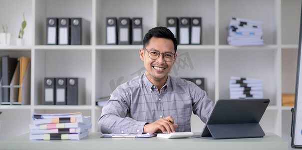 35 岁左右年轻英俊的亚洲 Ceo 经理商人中年男子坐在靠近窗户的办公室里，手牵着手看着相机，微笑着。