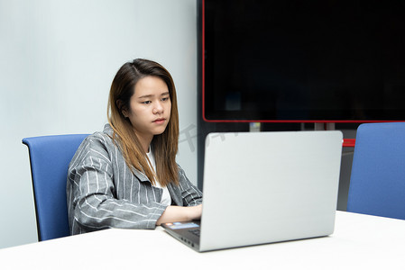 女性生气摄影照片_在办公室用笔记本电脑工作的女人很生气