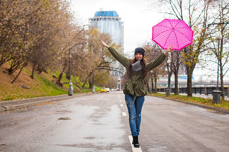 秋天雨天摄影照片_秋雨天带伞走路的年轻女子