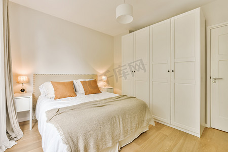 卧室台灯摄影照片_一间带大床和白色壁橱的卧室