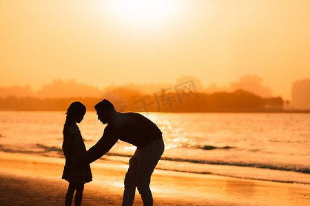 夕阳下的小女孩和爸爸剪影在海滩
