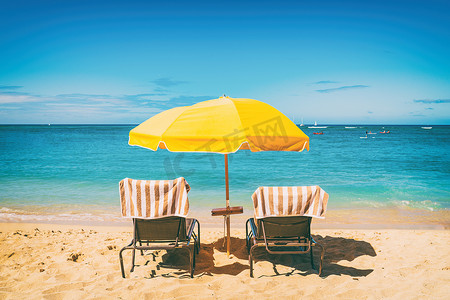 太阳伞度假背景下的海滩度假躺椅。