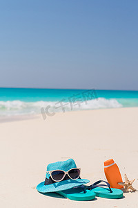 白色沙滩背景海洋上的防晒霜瓶、护目镜、海星和太阳镜