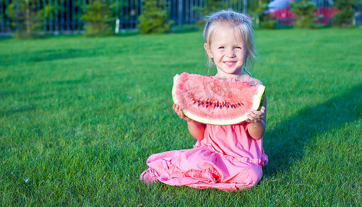 红色可爱西瓜摄影照片_手里拿着一块西瓜的可爱风趣小女孩