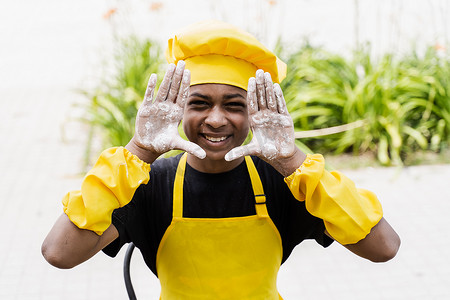 黑人非洲厨师少年双手捧着面粉，面带微笑。