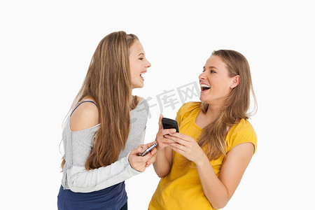 两个年轻女人拿着手机笑
